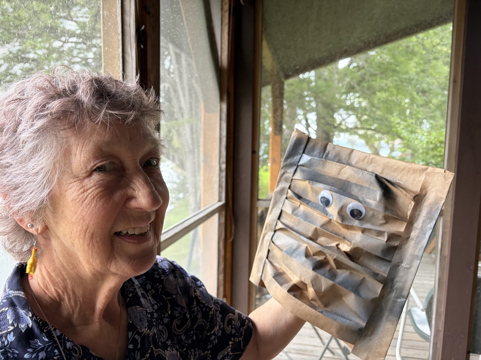 Carrie holding the Sedimentary rock puppet, a paper bag folded into layers with googly eyes