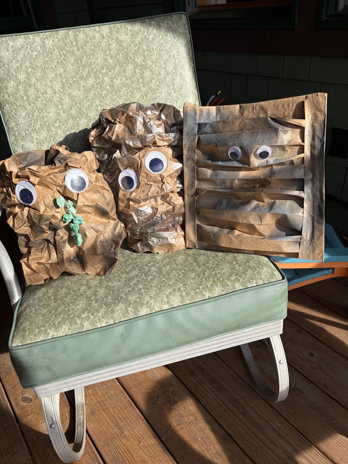 All three paper bag rock puppets sitting together on a porch chair